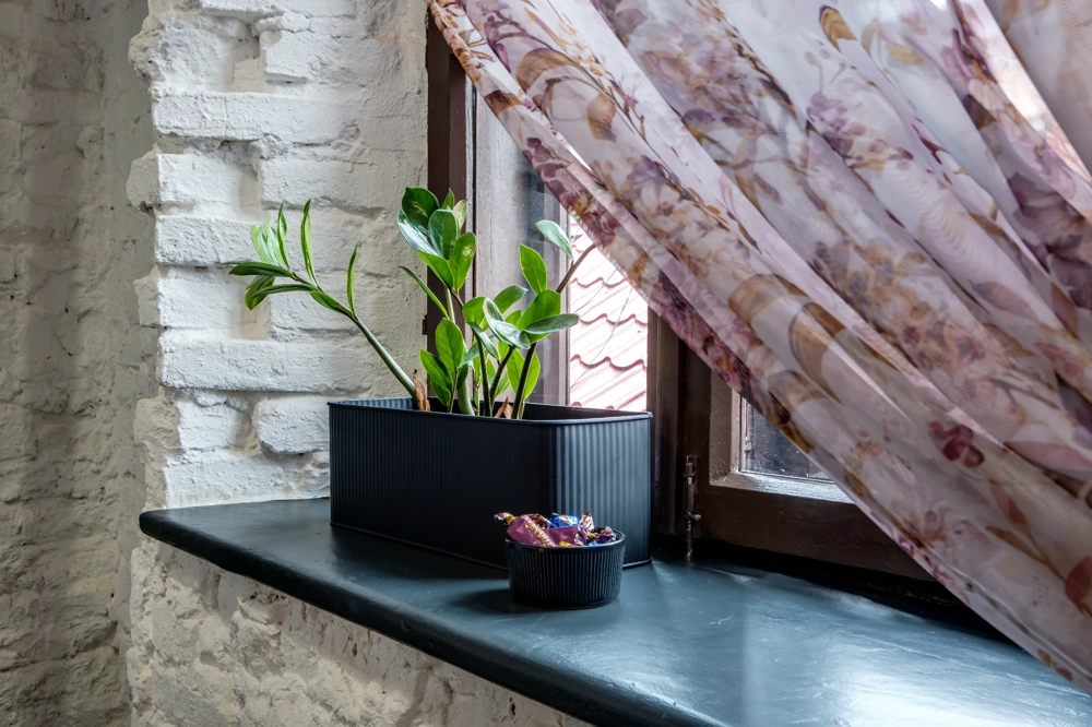 Schwarze Fensterbank mit Pflanzenkübel und Dekoschale als Beispiel für Fensterbänke innen