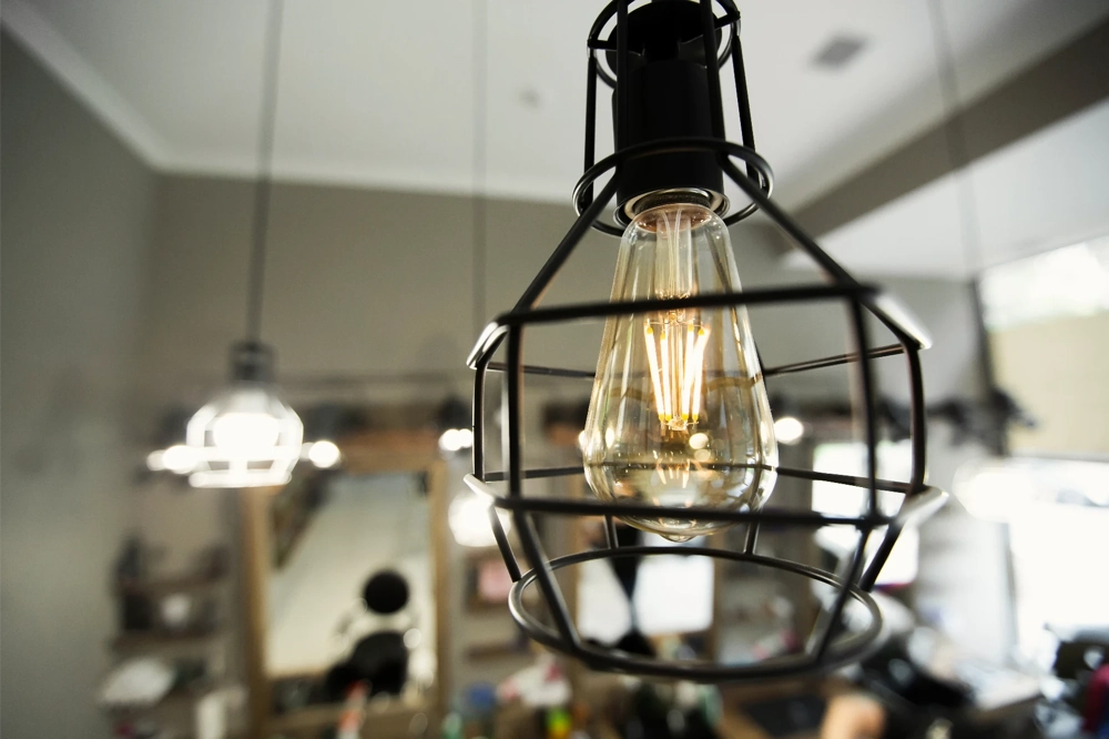 Industrielle Hängeleuchte mit Edison-Glühfaden im schwarzen Metallkäfig als Beleuchtung