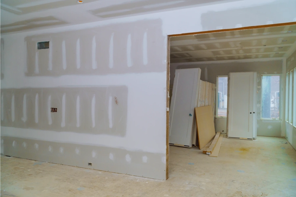 Heller Wohnraum im Rohbau mit frisch montierten Rigipsplatten und Türöffnung für Trockenbauarbeiten