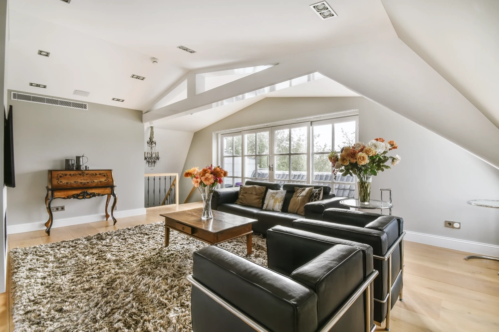 Helles Dachausbau-Wohnzimmer mit Parkettboden, weiß verputzten Wänden und modernen Sitzmöbeln